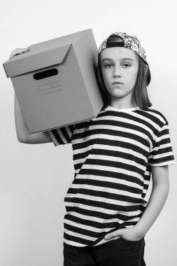 Beyaz arka planda kutuyu tutan gülümseyen genç. Karton paketli bir çocuk. Teslimat Konsepti. Kargocu çocuk elinde bir karton kutu tutuyor..