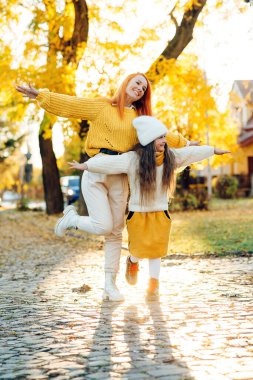 Sonbahar yürüyüşünde annesi gülen güzel bir kız. Sonbahar tatili, yaşam tarzı. Mutlu aile sonbahar parkında oynuyor..