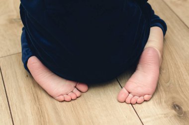 Evde dört ayak üstünde yalın ayak sürünen bir bebek. Çocuk bakımı konsepti. İlk adımlar yakın plan.