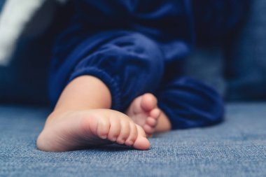 Kanepenin üzerinde şirin bebek ayakları var. Küçük kız evde çıplak ayakla oynuyor. Çocuk bakımı kavramı.