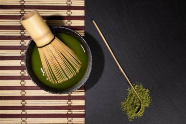 Bir kase siyah kibrit çayı, gri lekeli çırpı ve bambu kaşıklı masa örtüsü yeşil çaylı eski çimento arka planı lekeli, üst manzaralı, metin için yeri olan. 