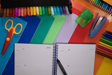 okul veya ofis malzemeleri, renkli defterler açık bir günlük ve kalem, kalemler, kalemler, keçeli kalemler, makas, kalem açacağı ve metin için 2023 yılına ait fotoğraf ve zımba..