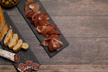 Yiyecek konsepti: İber ürünleri, sosisler, serrano jambonu, salam, zeytin ve ekmek tahta tabaklar üzerinde. İber usulü pişmiş et..