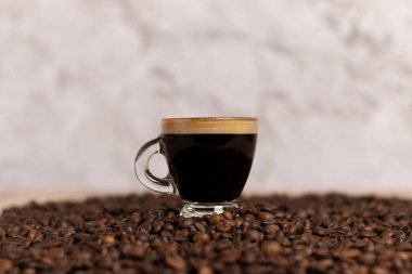 Şeffaf bardakta köpüklü sade kahve ve bilye sırtı kahve sehpasında cam kaide ve mesaj için yeri olan bir kahve.