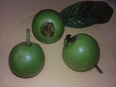 Sarı tabakta üç yeşil guava, lezzetli ve sağlıklı meyveler, yeşil yaprak