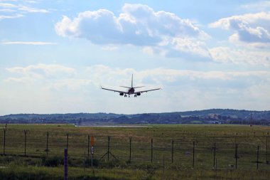 Yandan bir uçak iniş için yaklaşıyor, bulutların arkasına doğru. Pistin hemen üstünde..