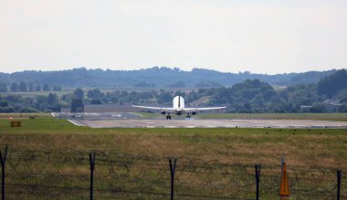 Yandan bir uçak iniş için yaklaşıyor, bulutların arkasına doğru. Pistin hemen üstünde..
