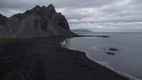 Aerial shot of the volcanic mountains in black sand beach in Iceland. The black sand is due to ashes of the previous volcanic eruptions