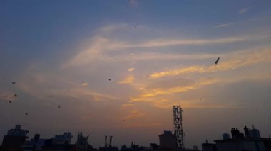 Gökyüzünde uçan uçurtmalarla gün batımının muhteşem manzarası