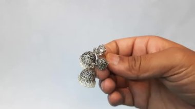 Beyaz bir arka planda beyaz bir kalp şeklinde kolye tutan el.