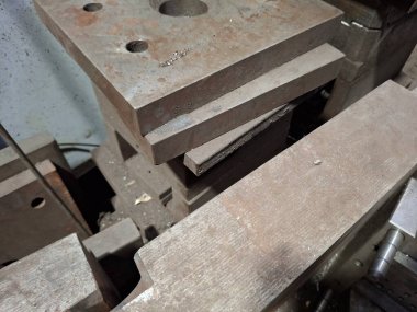 Bir sürü metal parçası olan ahşap bir masaya yakın.