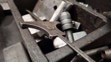 Bir atölyedeki ahşap bir masada metal bir anahtarın ve bir çekicin yakın plan çekimi.