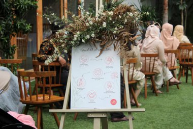 Alçak açıyla çekilen kahverengi ve beyaz sandalyeler güzel bir park ya da bahçenin arka planına karşı sahilde hazırlanıyor. Tropikal bir ülkede düğün ve kutlama