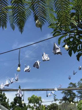Açık hava bahçesinde origami turnaları ya da mavi gökyüzü arka planı ve yeşil yapraklı parklar