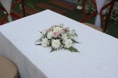 Alçak açıyla çekilen kahverengi ve beyaz sandalyeler güzel bir park ya da bahçenin arka planına karşı sahilde hazırlanıyor. Tropikal bir ülkede düğün ve kutlama