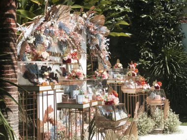 Alçak açıyla çekilen kahverengi ve beyaz sandalyeler güzel bir park ya da bahçenin arka planına karşı sahilde hazırlanıyor. Tropikal bir ülkede düğün ve kutlama