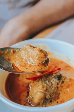 İnsanlar körili tavuk yiyor, kerala tarzı körili tavuk geleneksel olarak hindistancevizini kullanıyor ve grafit bir çarşafın üzerine yerleştirilmiş siyah seramik bir kap içinde sıralanıyor.