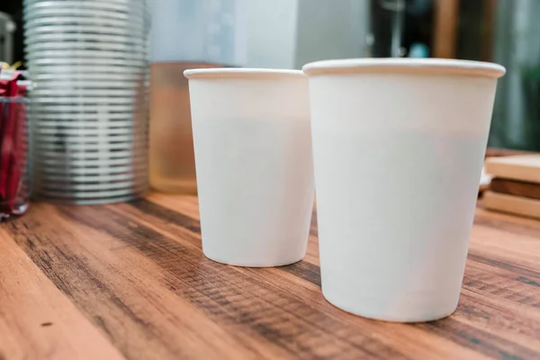 white paper cups of coffee mock up on blank background. two cups on table