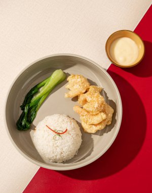 Un kızartılmış karides üzerine mayonez sosu serpilmiş ve sıcak pirinçle servis edilmiş.