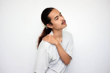 Genç Asyalı adam beyaz arka planda izole edilmiş acı ifadesiyle ensesine dokunuyor..