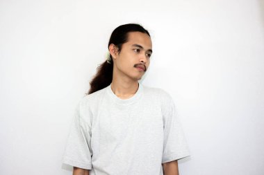 Gri tişörtlü, uzun saçlı Asyalı adam uyandıktan sonra tembellik ediyor. beyaz arkaplanda izole