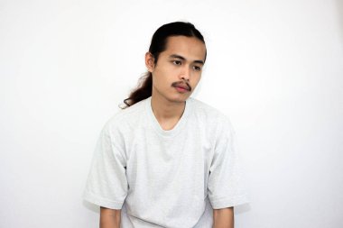 Gri tişörtlü, uzun saçlı Asyalı adam uyandıktan sonra tembellik ediyor. beyaz arkaplanda izole