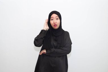 tesettürlü genç bir kadın ciddi ve meraklı görünüyor, dinliyor, gizli konuşmalar veya dedikodular duymaya çalışıyor, kulak misafiri oluyor.