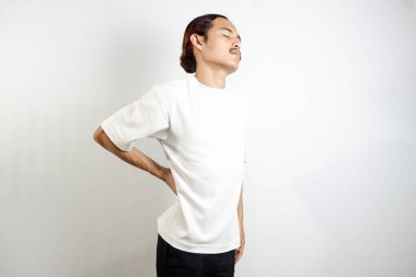 Beyaz tişört giyen genç adam genellikle kas hasarından kaynaklanan bel ağrısına maruz kalıyor. beyaz arkaplanda izole