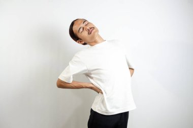 Beyaz tişört giyen genç adam genellikle kas hasarından kaynaklanan bel ağrısına maruz kalıyor. beyaz arkaplanda izole