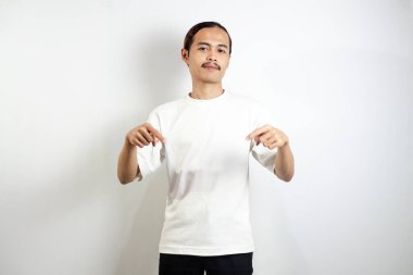 Beyaz tişörtlü Asyalı adam yukarı bakıyor. Beyaz stüdyo arka planında izole.