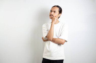 Genç Asyalı adam. Beyaz bir tişört giyiyor. Düşünceli bir ifadeyle. beyaz arkaplanda izole