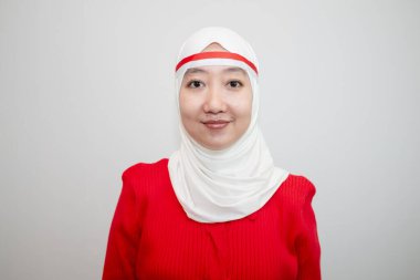 Beyaz tesettürlü, kırmızı kazaklı bir kadın. Endonezya 'nın bağımsızlık gününü kutluyoruz. Öne bak. Beyaz arkaplanda izolasyon.