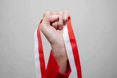 Bir kadının eli Endonezya bayrağının bir sembolü olarak kırmızı ve beyaz bir kurdele tutar. Beyaz arkaplanda izole