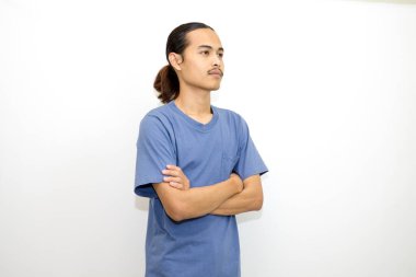 Koyu mavi tişört giyen gülümseyen Asyalı adam kollarını yana doğru kavuşturmuş duruyor. beyaz arkaplanda izole