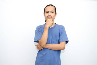 Koyu mavi tişört giyen gülümseyen Asyalı adam elleri çenesinde duruyor. beyaz arkaplanda izole