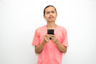 Asyalı, Endonezyalı bir adam cep telefonunu çenesinde tutuyor. Çok düşünüyor, işini düşünüyor ya da bir çözüm bulmak için okul ödevini düşünüyor. Beyaz arkaplanda izole