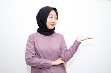 Endonezyalı Asyalı kadın portresi gömlek ve tesettürlü bir ve iki elle sağa, sola ve öne bakıyor. Beyaz arka planda izole edilmiş boş reklam alanına işaret ediyor.