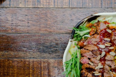 Fındıklı ve soslu sığır eti salatası, ahşap bir masanın üzerine yerleştirilmiş. Resim ayrıca metin için alan içerir, özelleştirilebilir bir düzen için ideal