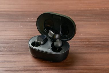 İzole edilmiş bir çift siyah TWS ya da Gerçek Kablosuz Stereo kulaklıklar düz bir yüzeye yerleştirilir, parlak tasarımları ve modern teknolojileri sergilenir.