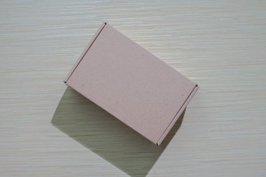 Bir masaya izole edilmiş kahverengi bir karton kutu. Paketleme veya hediye etmek için mükemmel. Basit ve çevre dostu bir tasarım ve maket sunuyor.