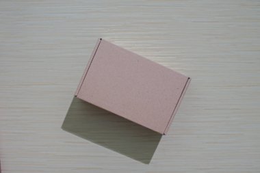 Bir masaya izole edilmiş kahverengi bir karton kutu. Paketleme veya hediye etmek için mükemmel. Basit ve çevre dostu bir tasarım ve maket sunuyor.