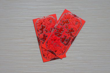 Çin Yeni Yılı 'nda para hediye etmek için kullanılan geleneksel kırmızı bir angpao, iyi şans ve refahı simgeleyen bir ahşap masa arkasında izole edilmiş.