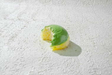 Isırık izi olan küçük bir donut, beyaz bir arka plan üzerine kurulmuş, tat ve dokuyu işaret ediyor.