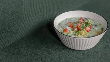 Taze domates dilimleriyle kaplanmış sıcak ve lezzetli tavuk lapası, rahatlatıcı ve tatmin edici bir yemek için servis edilmiş..