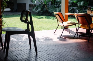 Ahşap masa ve sandalye, minimalist ve sakin bir atmosferin altında kırmızı tuğla döşemeli bir kafeterya alanında..