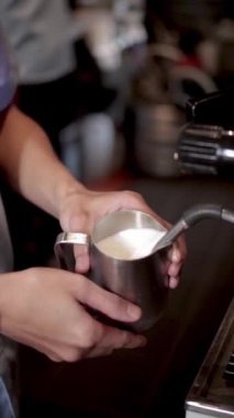 Kahveci kahve için buğulanmış süt hazırlıyor.