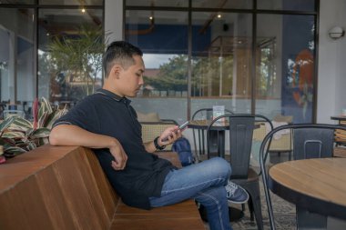 Adam rahat bir kafe atmosferinde oturmuş, rahat bir ortamda rahatlık ve rahatlığın tadını çıkarıyor..