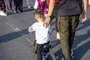 Bir baba oğluna küçük bir bisiklette rehberlik eder.