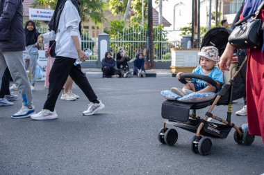 Paved Caddesi 'nde bebek arabasında oturan genç bir çocuk.