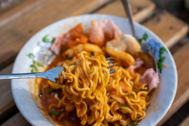 Baharatlı yemek kasesinden çatal kaldıran eriştenin yakın çekimi